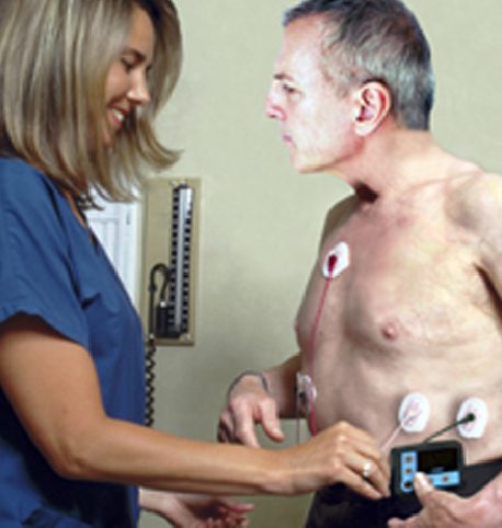 A nurse is holding an ecg device on a man's chest.